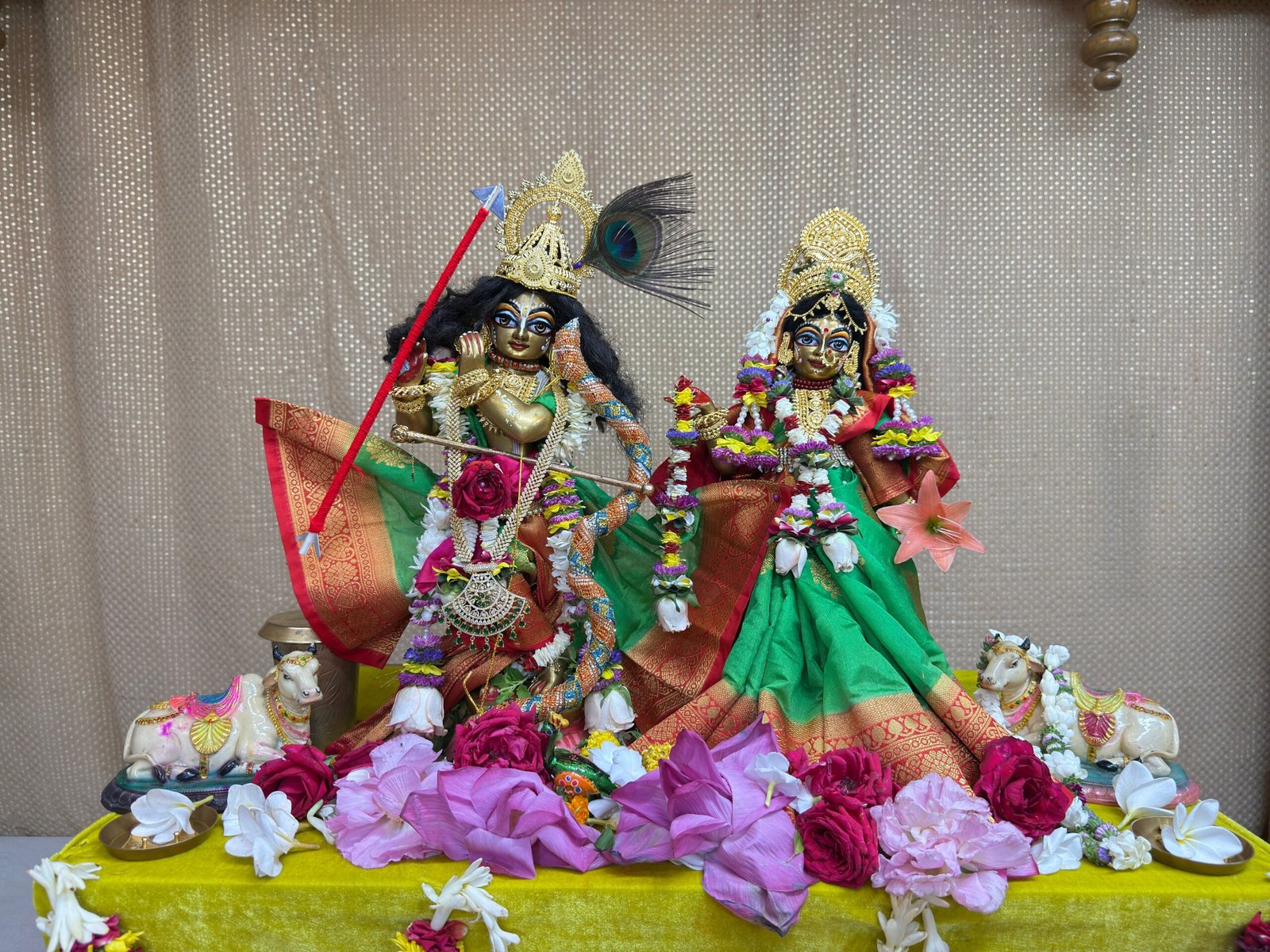 Vibrant statues of Hindu deities adorned with flowers, depicting a traditional ritual setup.